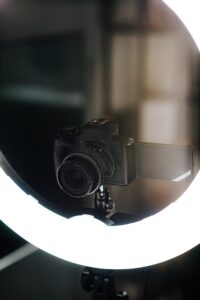 From above of modern photo camera near contemporary circle studio lamp on blurred background