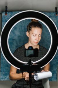Young female examining notes in notebook in professional studio with photo camera and studio lamp